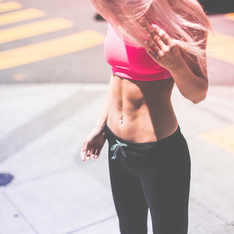 Woman wearing pink sports bra and showing off abs